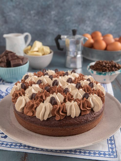 Torta al cioccolato e caffè decorata con ciuffi di crema alternati e chicchi di caffè al cioccolato