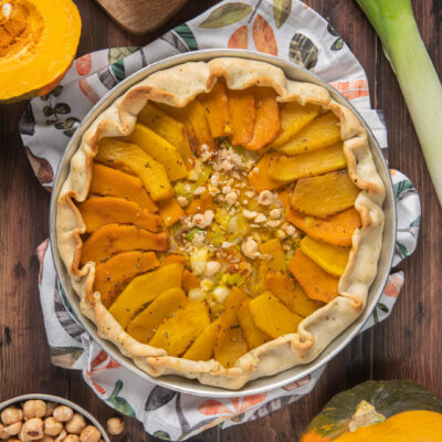 Torta salata zucca e nocciole con fette disposte a raggiera e granella al centro