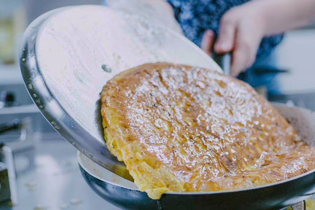 Frittata dorata capovolta su un coperchio piatto prima di rientrare in padella