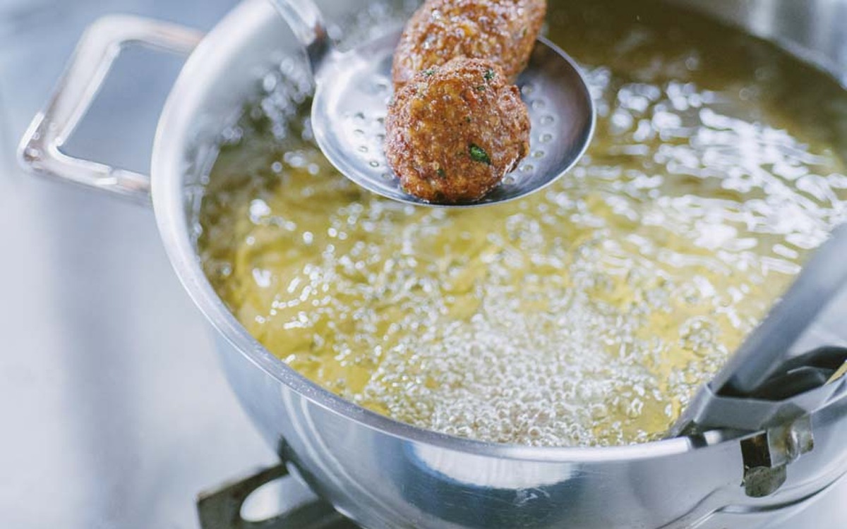 Polpette fritte sollevate dall'olio bollente con un mestolo forato