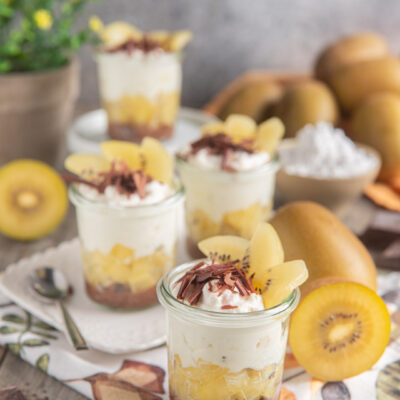 Bicchierino con yogurt, cioccolato e kiwi giallo a strati, guarnito con scaglie e fette fresche