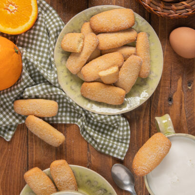 Biscotti da inzuppo spolverati di zucchero serviti con latte e arancia