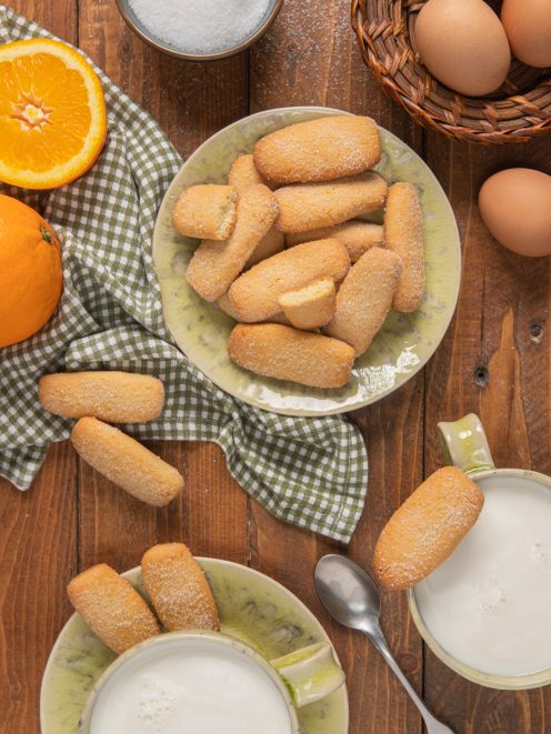 Biscotti da inzuppo spolverati di zucchero serviti con latte e arancia