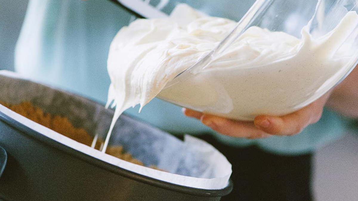 Crema al formaggio cremosa versata sulla base di biscotti nello stampo