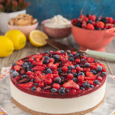 Cheesecake ai frutti di bosco con strato cremoso, gelatina rossa e mirtilli, fragole e ribes in superficie