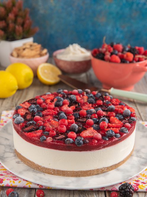 Cheesecake ai frutti di bosco con strato cremoso, gelatina rossa e mirtilli, fragole e ribes in superficie