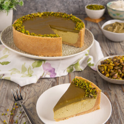 Cheesecake al pistacchio con crema verde, glassa lucida e granella di pistacchio sul bordo, servita a fetta