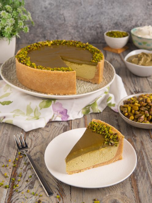 Cheesecake al pistacchio con crema verde, glassa lucida e granella di pistacchio sul bordo, servita a fetta