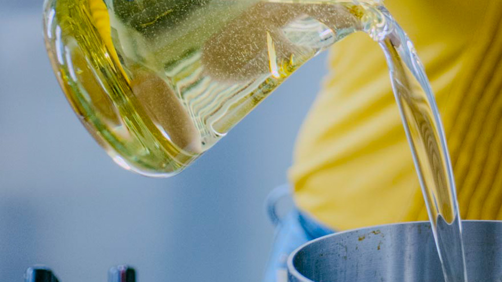 Olio di arachidi versato da un bricco in un tegame per la frittura