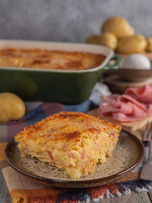 Gateau di patate con prosciutto cotto e formaggio filante, servito a fetta con crosta dorata