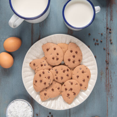 Gocciole con gocce di cioccolato servite con latte e ingredienti intorno