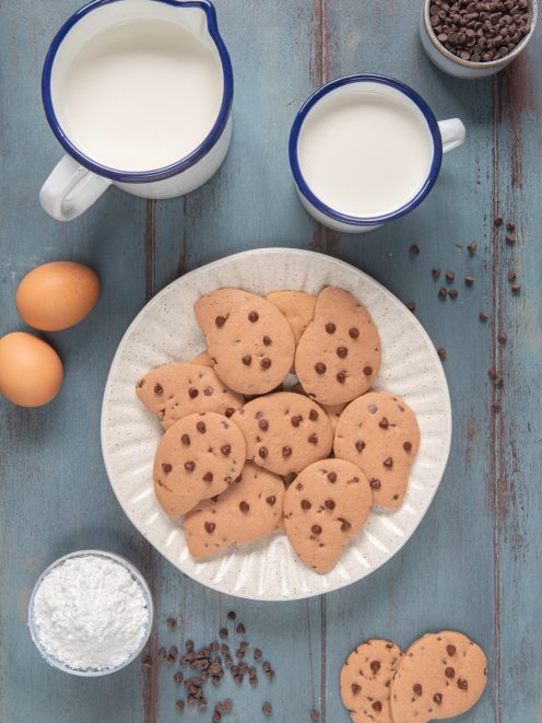 Gocciole con gocce di cioccolato servite con latte e ingredienti intorno