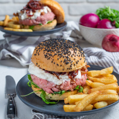 Hamburger di battuta di vitello con panino ai semi neri, burrata e confettura, servito con patatine fritte