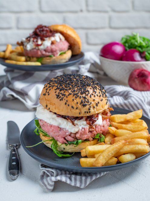 Hamburger di battuta di vitello con panino ai semi neri, burrata e confettura, servito con patatine fritte