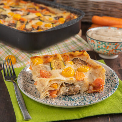 Lasagne di verdure con zucchine, pomodorini gialli e besciamella gratinata servite a fetta