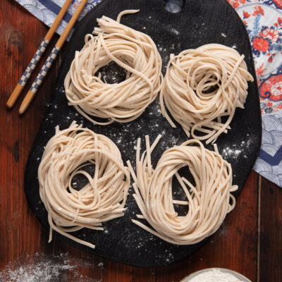 Quattro nidi di noodles freschi crudi infarinati, pronti per la cottura