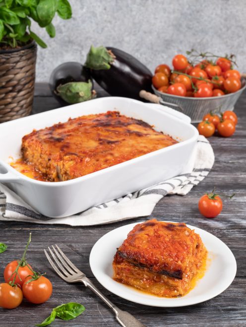 Parmigiana di melanzane appena sfornata con superficie dorata e caramellata, servita a fette