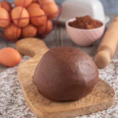 Pasta frolla al cacao appena impastata, a palla compatta su tagliere di legno