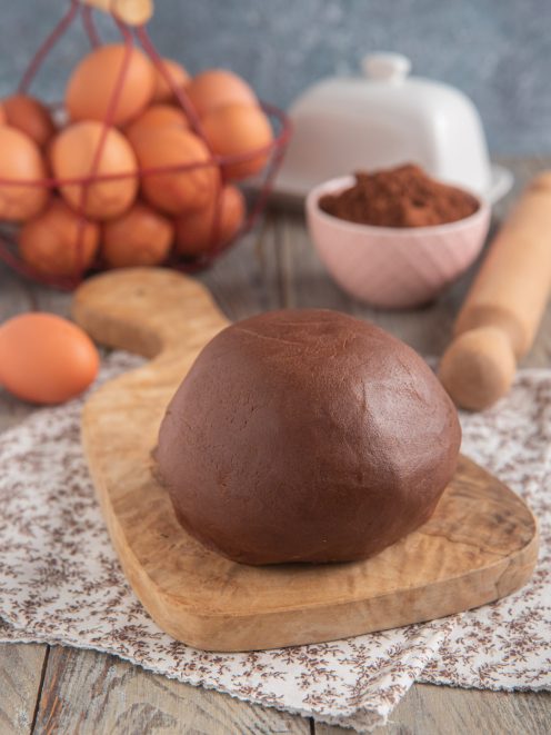 Pasta frolla al cacao appena impastata, a palla compatta su tagliere di legno