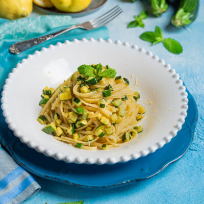 Pasta zucchine limone e menta con scorza grattugiata e foglie fresche in primo piano