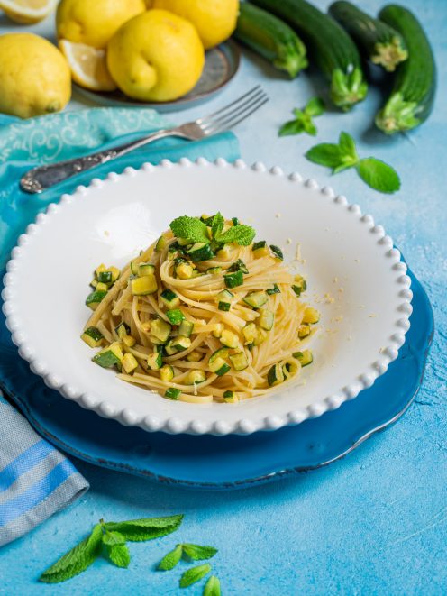 Pasta zucchine limone e menta con scorza grattugiata e foglie fresche in primo piano