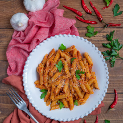 Penne all'arrabbiata con salsa di pomodoro piccante, parmigiano grattugiato e prezzemolo fresco