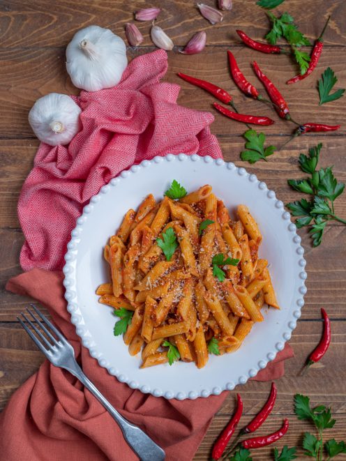 Penne all'arrabbiata con salsa di pomodoro piccante, parmigiano grattugiato e prezzemolo fresco
