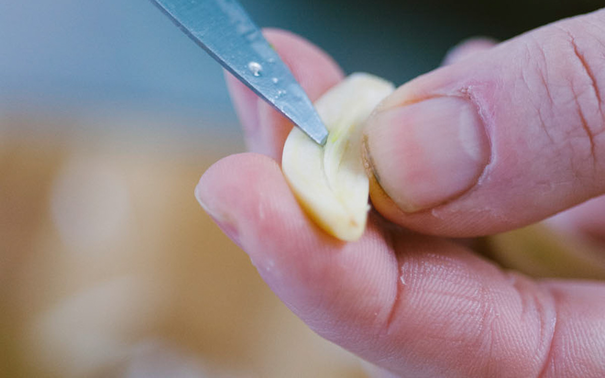 Mano che rimuove l'anima da uno spicchio d'aglio con la punta di un coltello