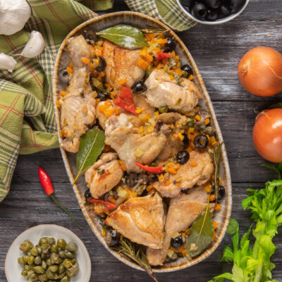 Pollo alla cacciatora in bianco con olive nere, peperoncino, carote e foglie di alloro