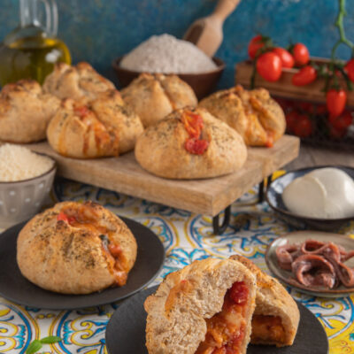 Strombolini ripieni di pomodoro e mozzarella filante, uno tagliato a meta per mostrare il cuore farcito