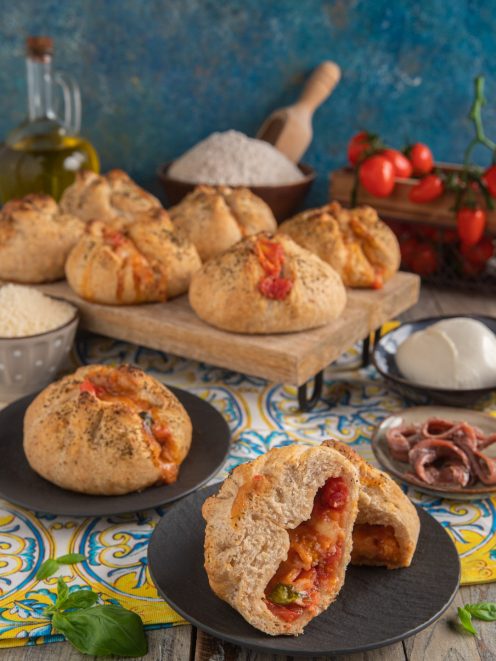 Strombolini ripieni di pomodoro e mozzarella filante, uno tagliato a meta per mostrare il cuore farcito