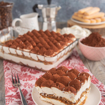 Tiramisù senza uova in fetta con strati di crema mascarpone, savoiardi al caffè e cacao in polvere