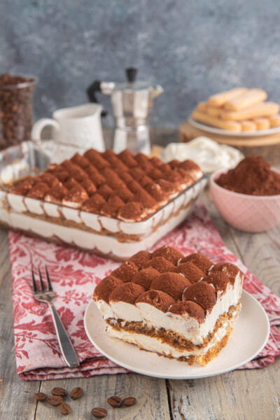Tiramisù senza uova in fetta con strati di crema mascarpone, savoiardi al caffè e cacao in polvere