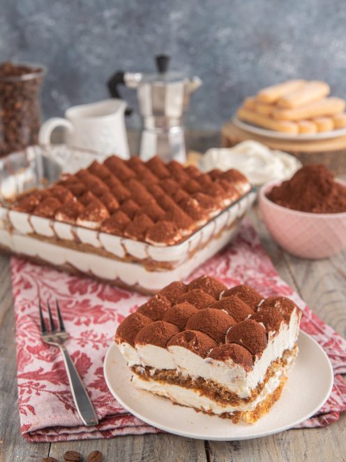Tiramisù senza uova in fetta con strati di crema mascarpone, savoiardi al caffè e cacao in polvere
