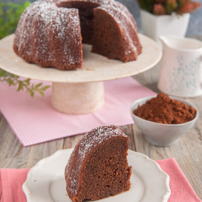 Torta al cacao senza uova tagliata a fette, spolverata di zucchero a velo e servita con cacao amaro