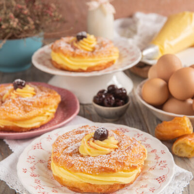 Zeppole di San Giuseppe farcite con crema pasticcera e amarene, spolverate di zucchero a velo