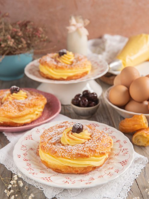 Zeppole di San Giuseppe farcite con crema pasticcera e amarene, spolverate di zucchero a velo