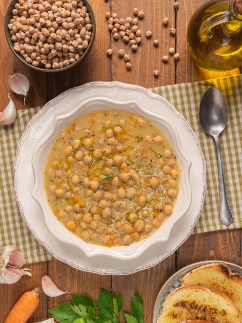 Zuppa di ceci densa con brodo dorato, verdure a pezzi e un filo d'olio, servita con crostini
