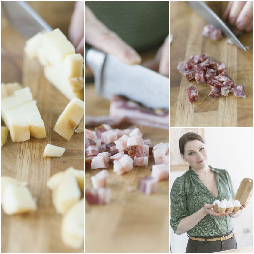 Provola, salame e pancetta tagliati a dadini sul tagliere, con uova fresche per il casatiello napoletano