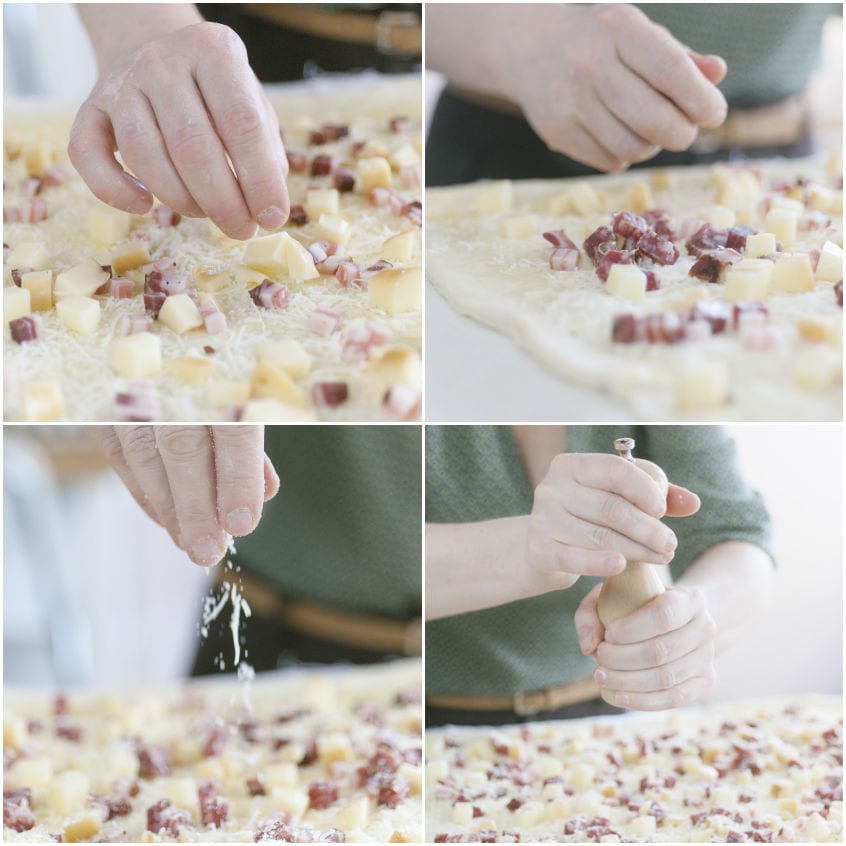Mani che distribuiscono cubetti di provola e salame sull'impasto del casatiello, poi aggiungono sale e pepe