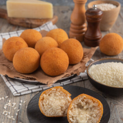 Arancini cacio e pepe dorati e croccanti, tagliati a metà per mostrare il ripieno filante di riso