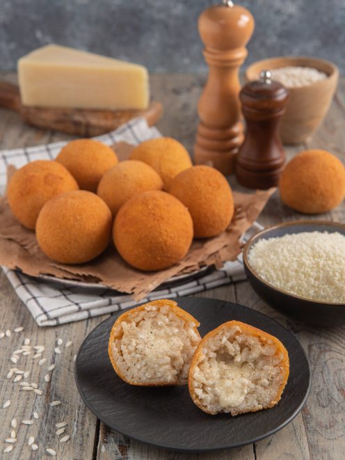 Arancini cacio e pepe dorati e croccanti, tagliati a metà per mostrare il ripieno filante di riso