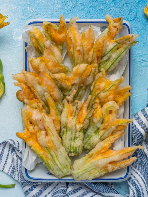 Fiori di zucca in pastella fritti, dorati e croccanti, serviti su carta assorbente