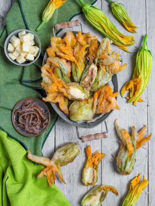 Fiori di zucca ripieni in pastella dorata con mozzarella filante e acciughe