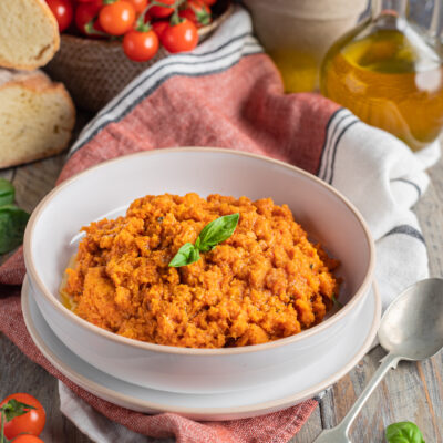 Pappa al pomodoro servita in ciotola, densa e rustica, guarnita con foglie di basilico fresco