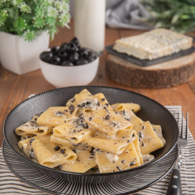Pasta alla cenere con salsa cremosa e olive nere tritate, servita in abbondante porzione