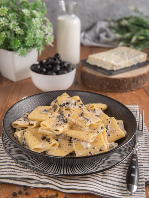 Pasta alla cenere con salsa cremosa e olive nere tritate, servita in abbondante porzione