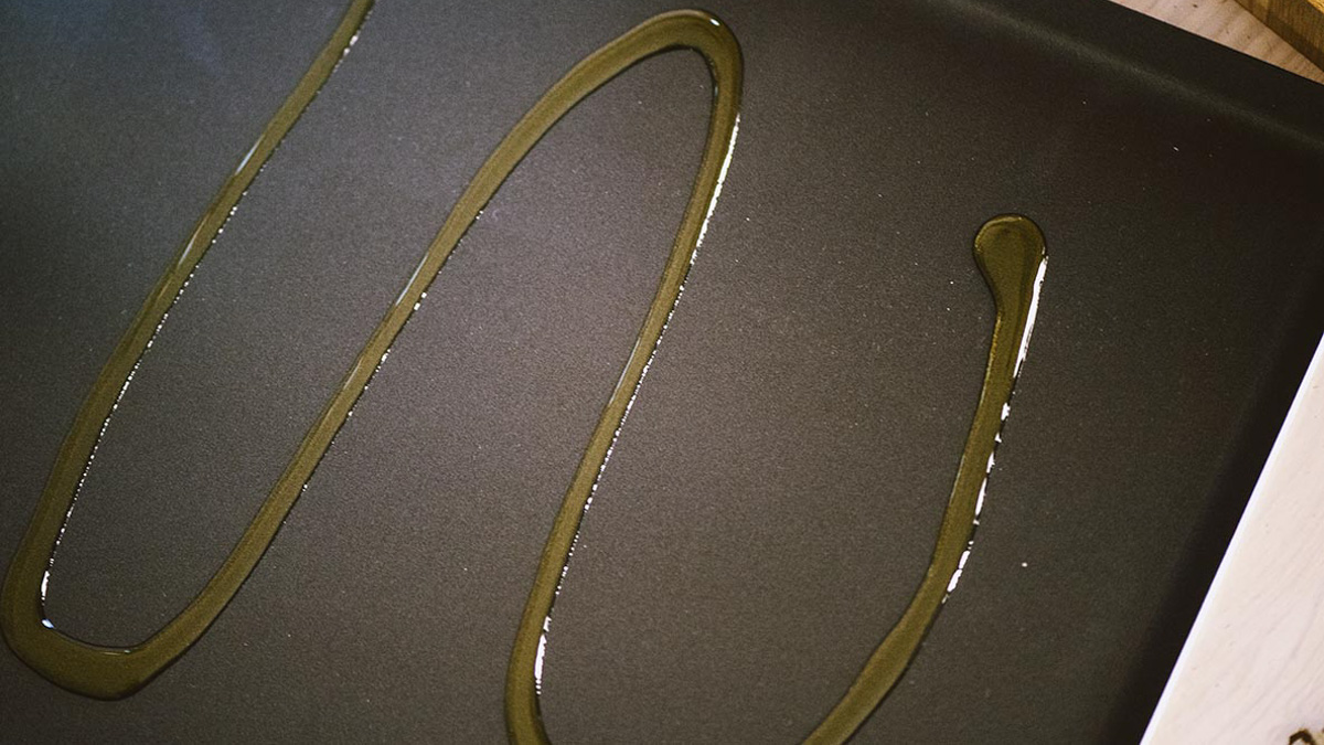 Olio versato a filo sulla teglia da forno ancora vuota, pronta per scaldarsi