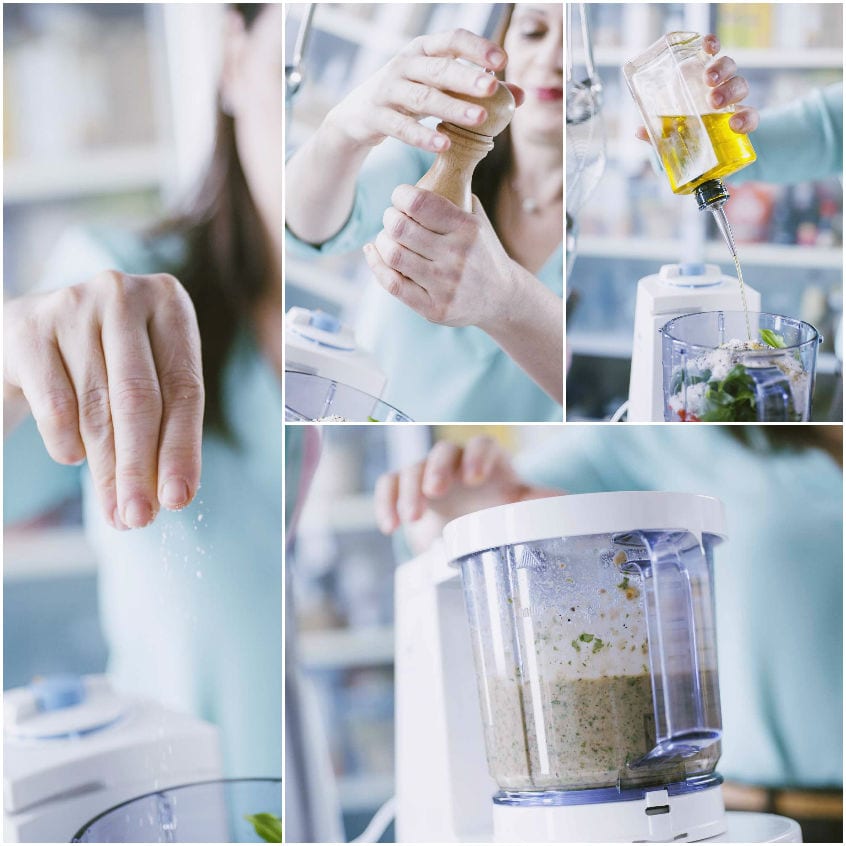 Olio extravergine versato nel food processor con il basilico per il pesto siciliano