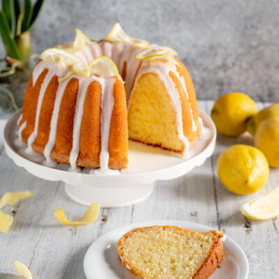 Ciambella al limone con glassa bianca colante e fettina tagliata che mostra la mollica soffice